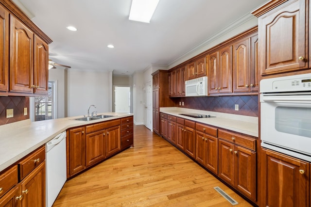 kitchen featuring kitchen peninsula, tasteful backsplash, white appliances, light wood-type flooring, and sink