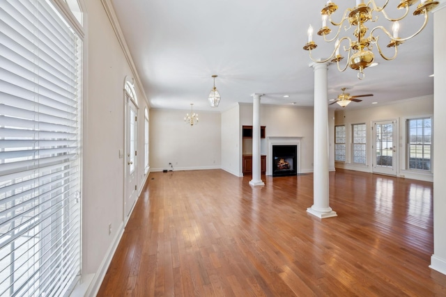 unfurnished living room featuring ornate columns, ornamental molding, ceiling fan with notable chandelier, and wood-type flooring