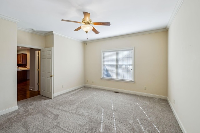 carpeted empty room with ceiling fan and crown molding