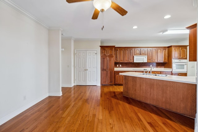 kitchen featuring white appliances, wood-type flooring, sink, ceiling fan, and crown molding