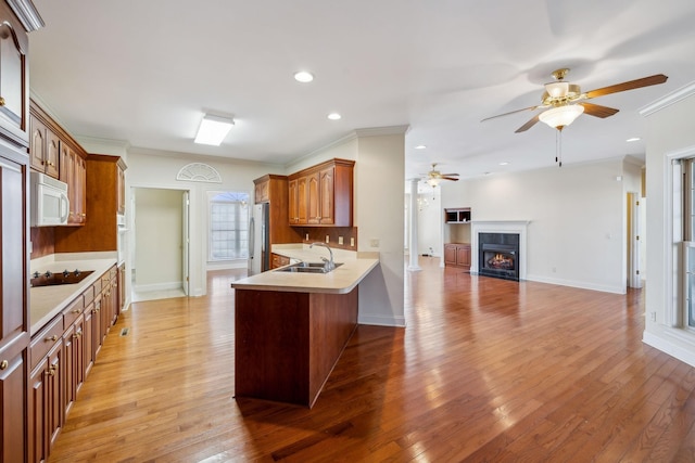 kitchen with kitchen peninsula, sink, crown molding, stainless steel fridge, and black electric cooktop