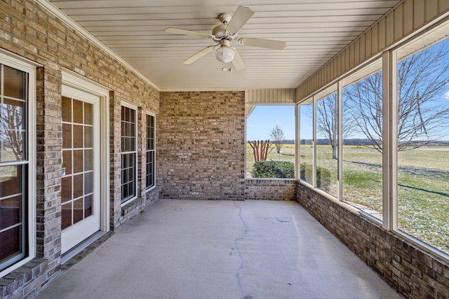 unfurnished sunroom featuring ceiling fan and a rural view