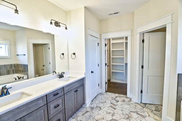 bathroom featuring toilet, a tub to relax in, and vanity