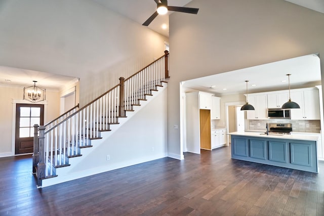 kitchen with decorative backsplash, white cabinetry, hanging light fixtures, stainless steel appliances, and dark hardwood / wood-style flooring