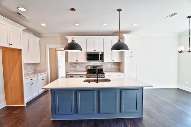 kitchen with decorative light fixtures, white cabinets, stainless steel appliances, and a center island with sink