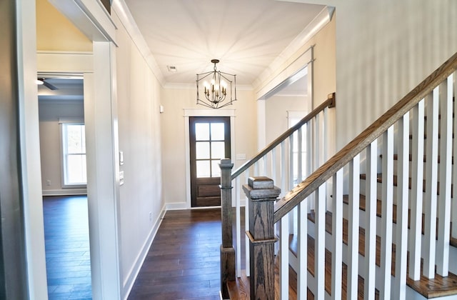 entrance foyer featuring dark wood-type flooring, crown molding, and a notable chandelier