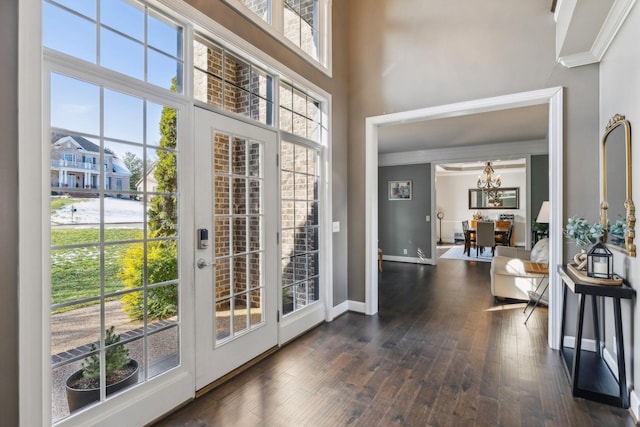 doorway with a towering ceiling, dark hardwood / wood-style flooring, crown molding, and french doors