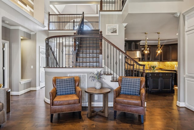 living area featuring dark wood-type flooring, crown molding, and a towering ceiling