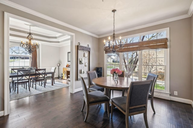 dining room with dark hardwood / wood-style floors, a tray ceiling, a chandelier, and ornamental molding