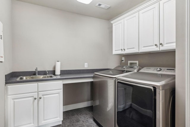 laundry area with cabinets, dark tile patterned floors, sink, and washing machine and dryer