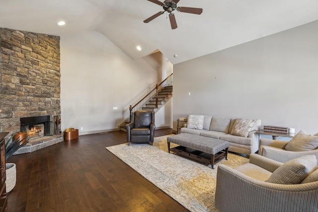 living room with ceiling fan, dark hardwood / wood-style floors, a stone fireplace, and vaulted ceiling