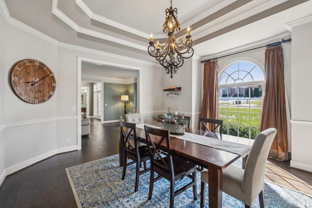 dining space with a tray ceiling, dark hardwood / wood-style flooring, ornamental molding, and a notable chandelier