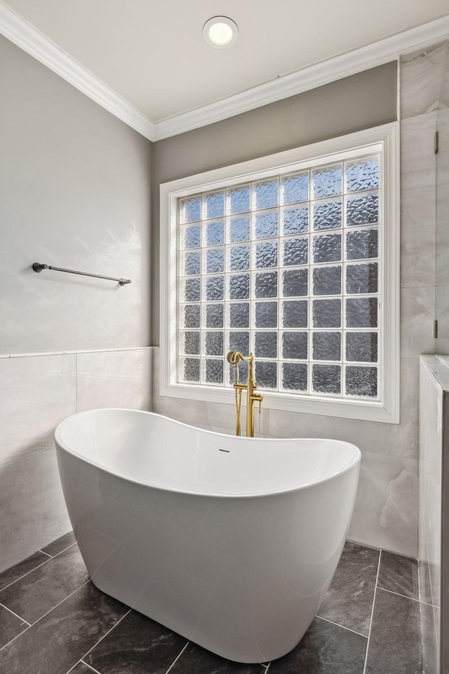 bathroom featuring tile walls, ornamental molding, and a bath