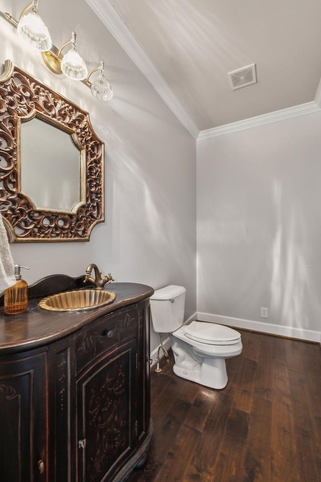 bathroom with toilet, crown molding, hardwood / wood-style flooring, and vanity