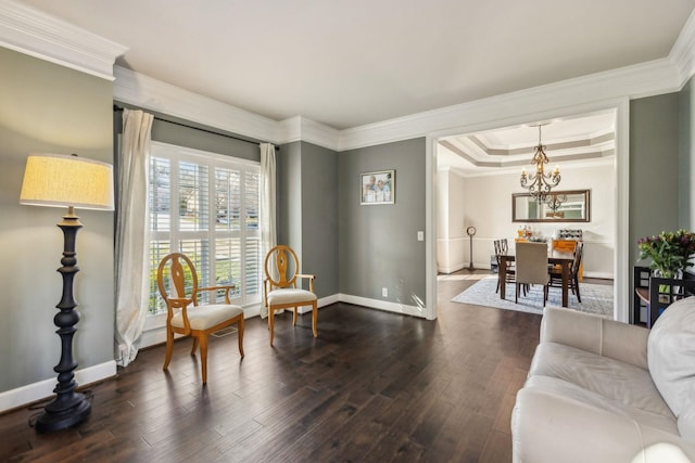 living room with dark hardwood / wood-style floors, a chandelier, crown molding, and a raised ceiling