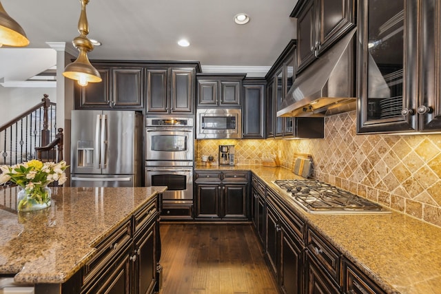 kitchen with stainless steel appliances, backsplash, hanging light fixtures, light stone countertops, and ornamental molding