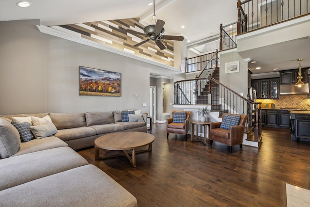 living room with ceiling fan, dark hardwood / wood-style flooring, and a towering ceiling