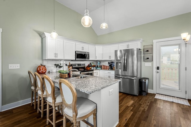 kitchen featuring white cabinets, stainless steel appliances, decorative backsplash, hanging light fixtures, and kitchen peninsula