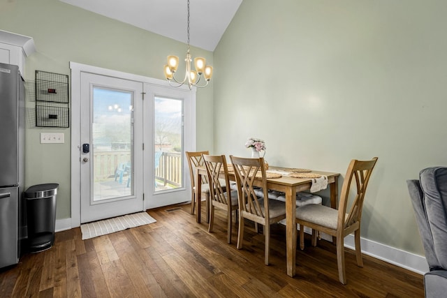 dining room featuring vaulted ceiling, dark wood-type flooring, and an inviting chandelier