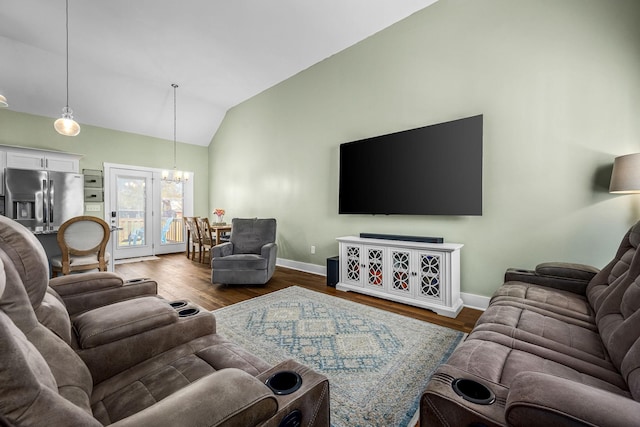 living room with dark wood-type flooring, lofted ceiling, and an inviting chandelier