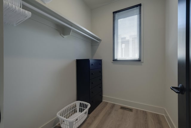 walk in closet with light hardwood / wood-style flooring