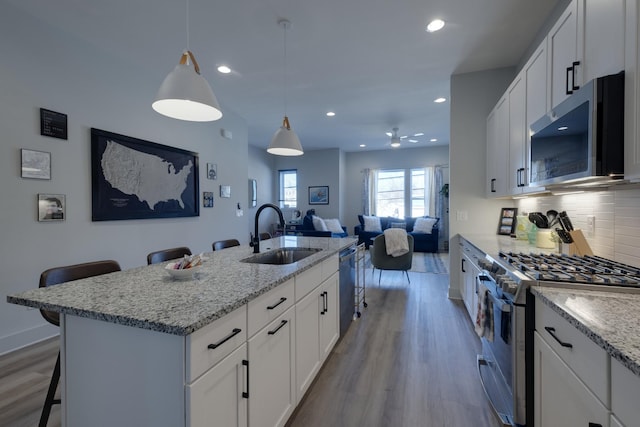 kitchen with white cabinets, appliances with stainless steel finishes, sink, and a breakfast bar area
