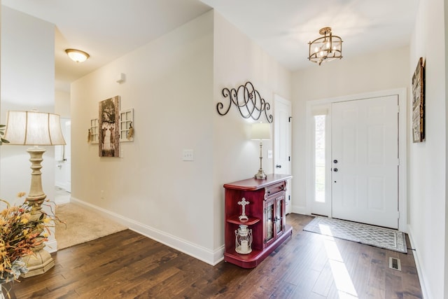 entrance foyer featuring dark hardwood / wood-style flooring and an inviting chandelier