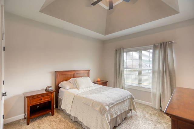 carpeted bedroom featuring ceiling fan and a tray ceiling