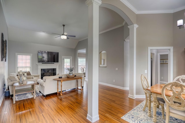 living room with ceiling fan, plenty of natural light, a tiled fireplace, and light wood-type flooring