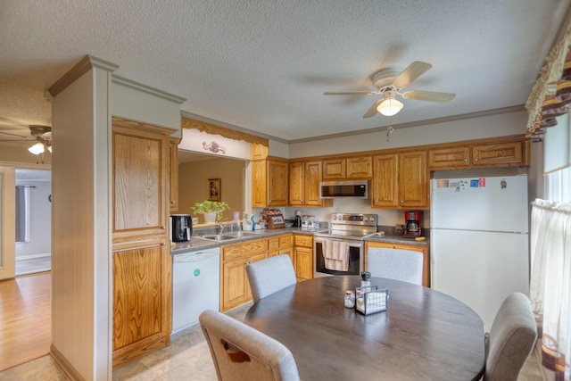 kitchen featuring ceiling fan, appliances with stainless steel finishes, a textured ceiling, ornamental molding, and sink