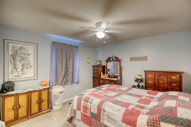 bedroom with ceiling fan, light carpet, and a textured ceiling