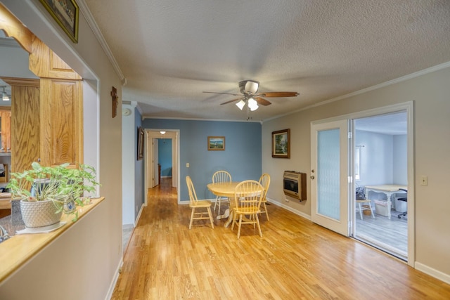 dining room with ceiling fan, light wood-type flooring, heating unit, a textured ceiling, and ornamental molding