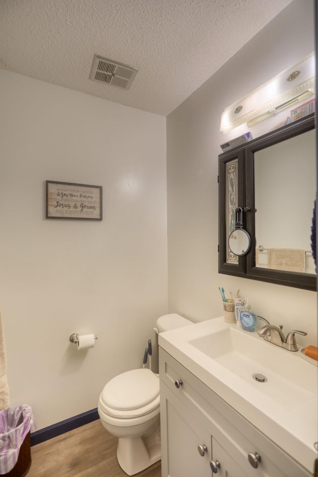 bathroom featuring a textured ceiling, toilet, wood-type flooring, and vanity