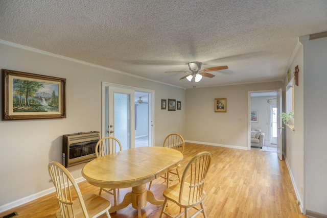 dining room with a textured ceiling, light hardwood / wood-style floors, ceiling fan, heating unit, and crown molding