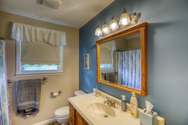 bathroom with toilet, vanity, a healthy amount of sunlight, and a textured ceiling