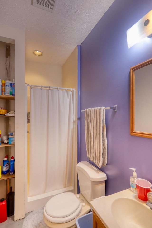 bathroom featuring a textured ceiling, toilet, walk in shower, and vanity