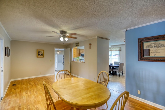 dining area featuring ceiling fan, a textured ceiling, light hardwood / wood-style flooring, and ornamental molding