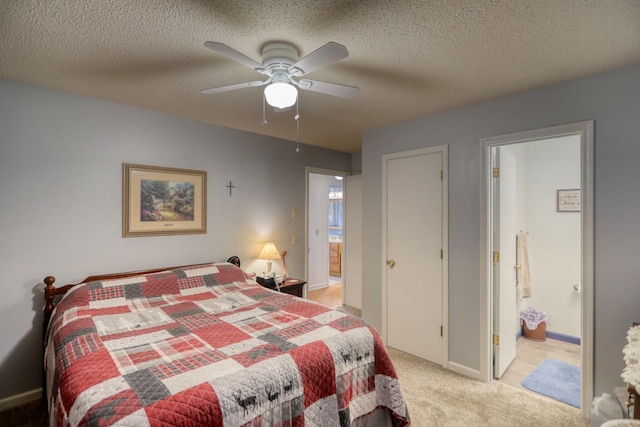 bedroom with a textured ceiling, ceiling fan, ensuite bathroom, and light carpet