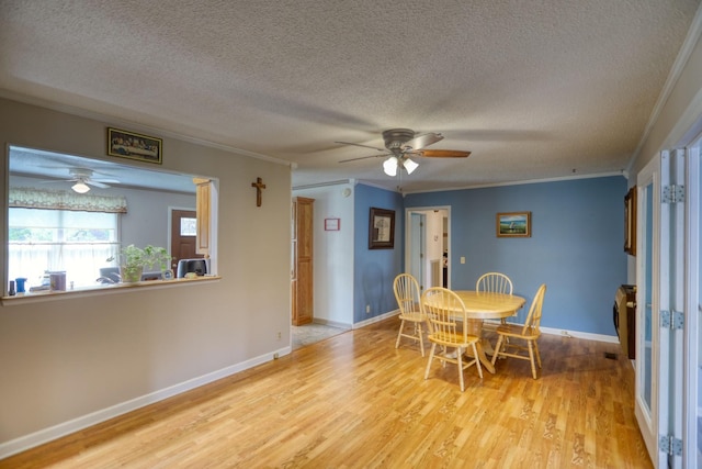 dining area featuring ceiling fan, a textured ceiling, light hardwood / wood-style flooring, and ornamental molding