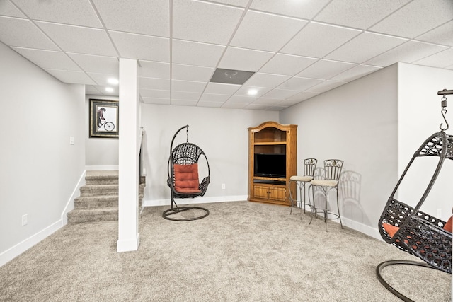 living area with a paneled ceiling and carpet flooring