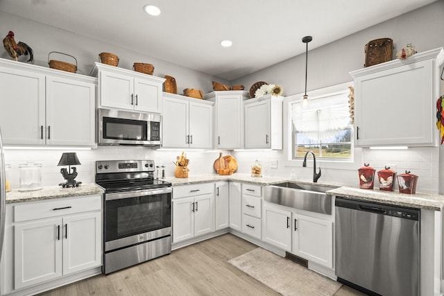 kitchen featuring sink, light hardwood / wood-style flooring, hanging light fixtures, stainless steel appliances, and white cabinets