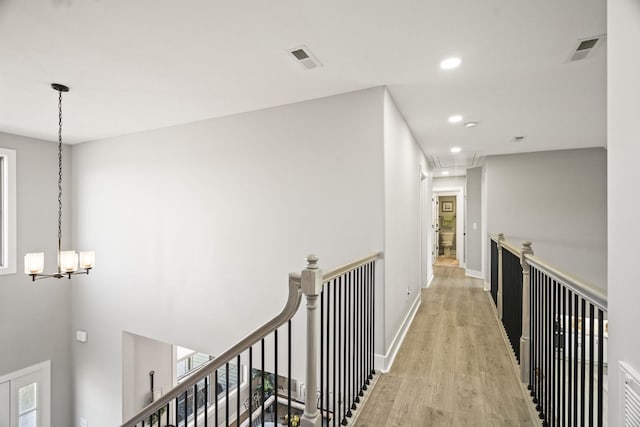 corridor featuring a notable chandelier and light hardwood / wood-style flooring