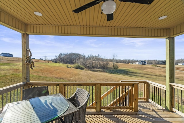 deck featuring ceiling fan, a lawn, and a rural view