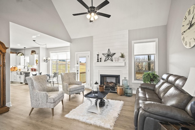 living room with a wealth of natural light, ceiling fan with notable chandelier, and light hardwood / wood-style flooring