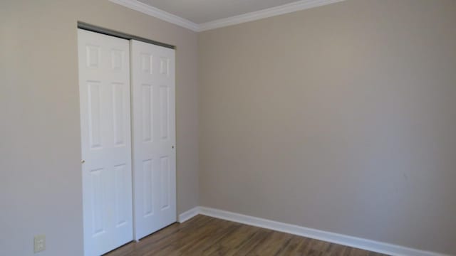 unfurnished bedroom with a closet, dark hardwood / wood-style floors, and crown molding