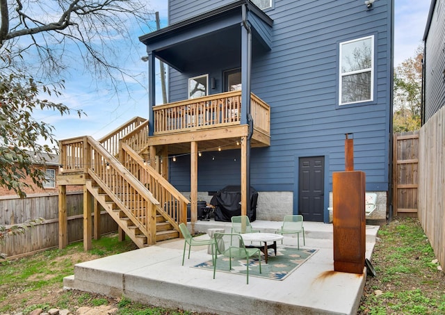 rear view of property with a wooden deck and a patio