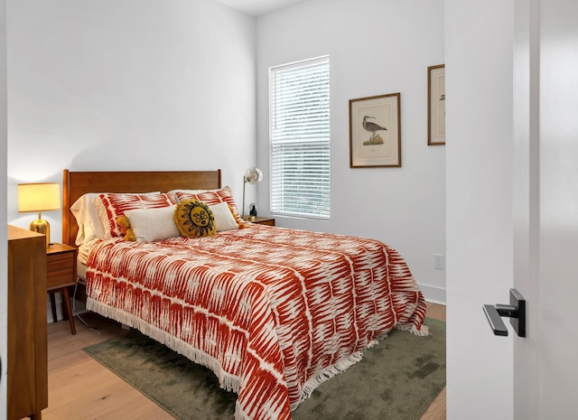 bedroom with multiple windows and light hardwood / wood-style flooring