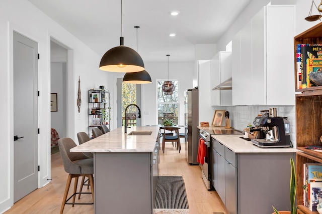 kitchen with a center island with sink, stainless steel appliances, backsplash, white cabinets, and sink