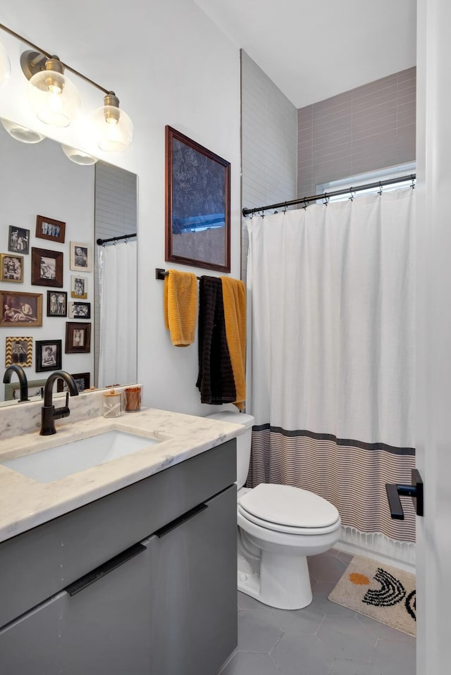 bathroom with toilet, vanity, and tile patterned flooring