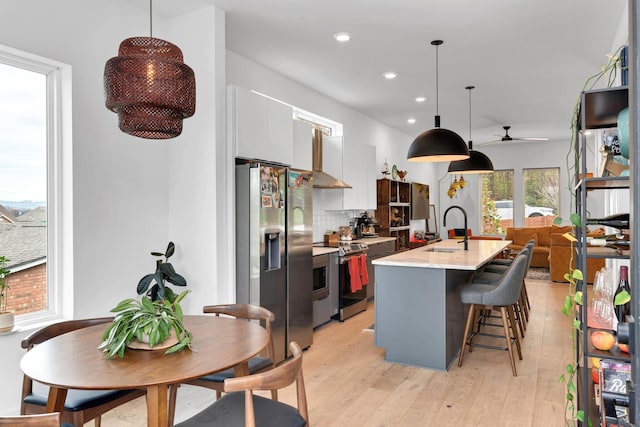 kitchen featuring pendant lighting, white cabinetry, stainless steel appliances, tasteful backsplash, and a kitchen island with sink